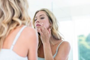 Woman looking in mirror, concerned about her skin